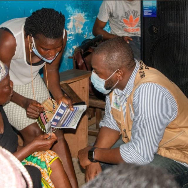 Field worker speaking with household members during outreach in Liberia